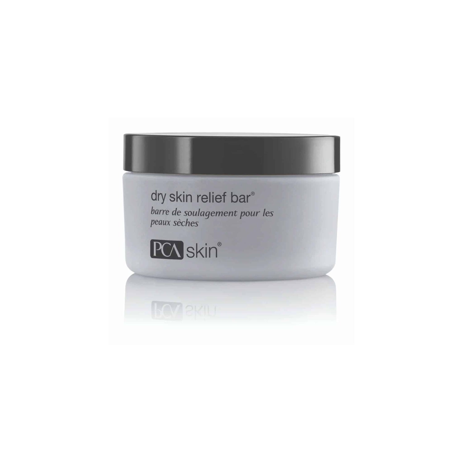 A white container with a black lid, labeled "Dry Skin Relief Bar" and "PCA Skin." The label includes both English and French text, with the French translation below the English description. This gentle cleansing bar is designed for skincare, ideal for those with dry skin.