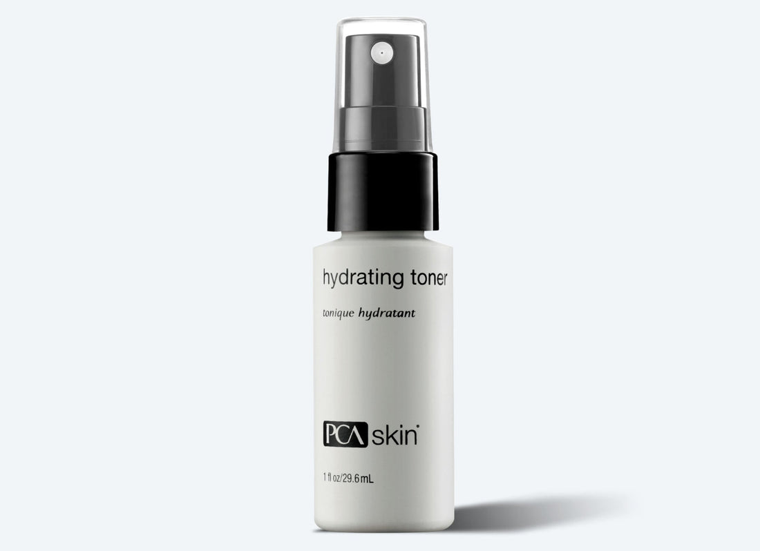A white 30 ml bottle of Hydrating Toner Spray by PCA Skin, featuring a black spray cap, stands against a light gray background. The label highlights "hydrating toner," "PCA Skin," and its antioxidant protection benefits.