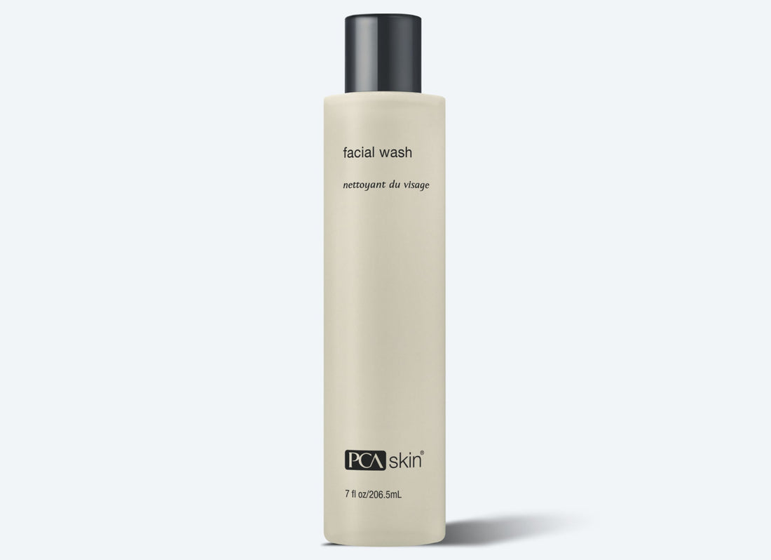 A beige bottle of Facial Wash with a black cap, suitable for normal and sensitive skin. The label features "facial wash" and "nettoyant du visage" in smaller text below, along with "PCA skin" at the bottom. This 7 fl oz (206.5 ml) product hydrates and exfoliates for a clean, refreshed complexion.