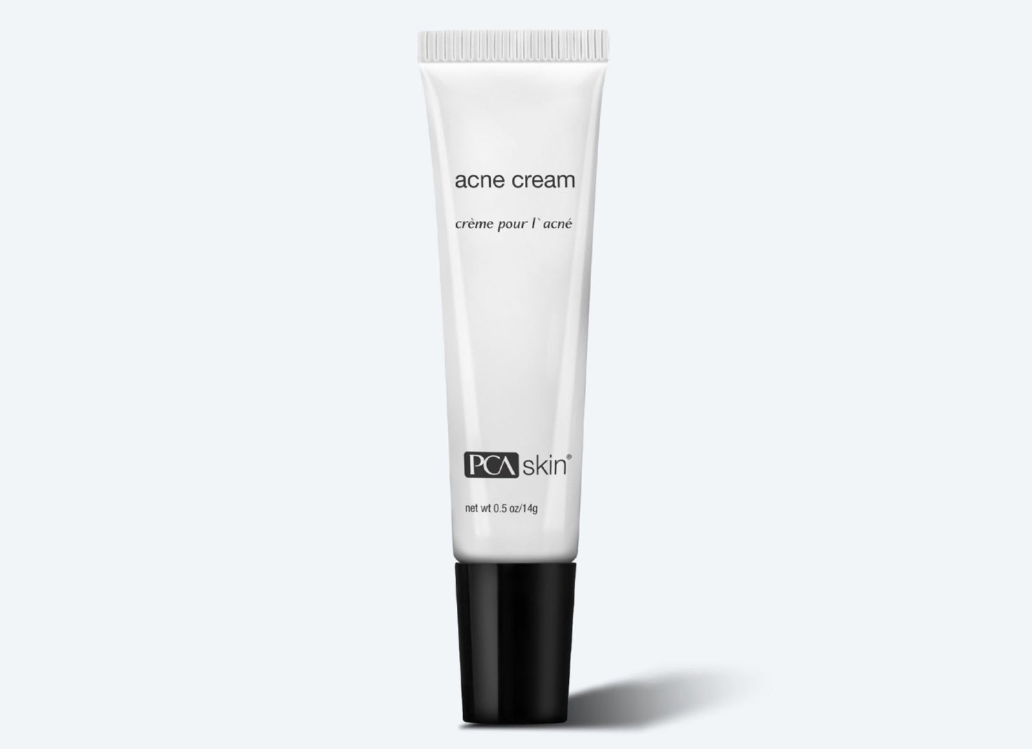 A white tube of Acne Cream with a black cap is displayed against a light grey background. The words "acne cream" and "crème pour l&