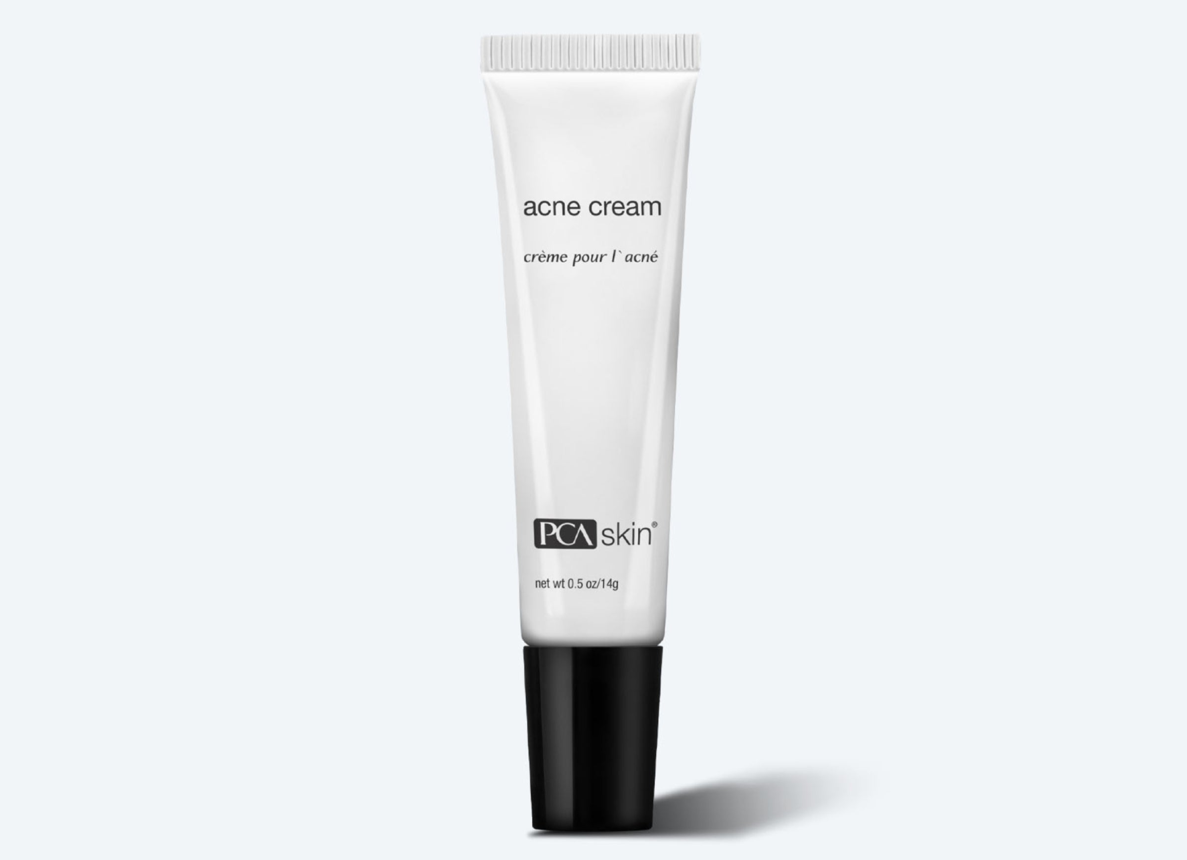 A white tube of Acne Cream with a black cap is displayed against a light grey background. The words "acne cream" and "crème pour l&