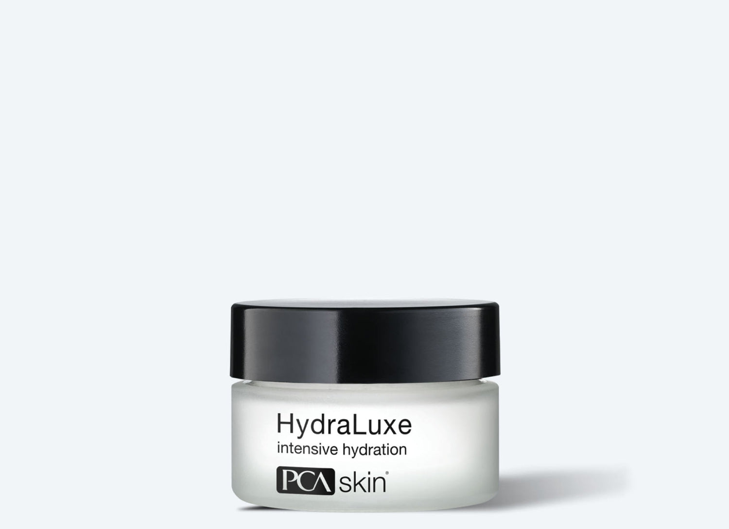 A product image of a frosted glass jar with a black lid, labeled "HydraLuxe Intensive Hydration" by PCA Skin. The white jar, featuring black text that highlights its ability to deeply hydrate and soften fine lines, is displayed against a light gray background.