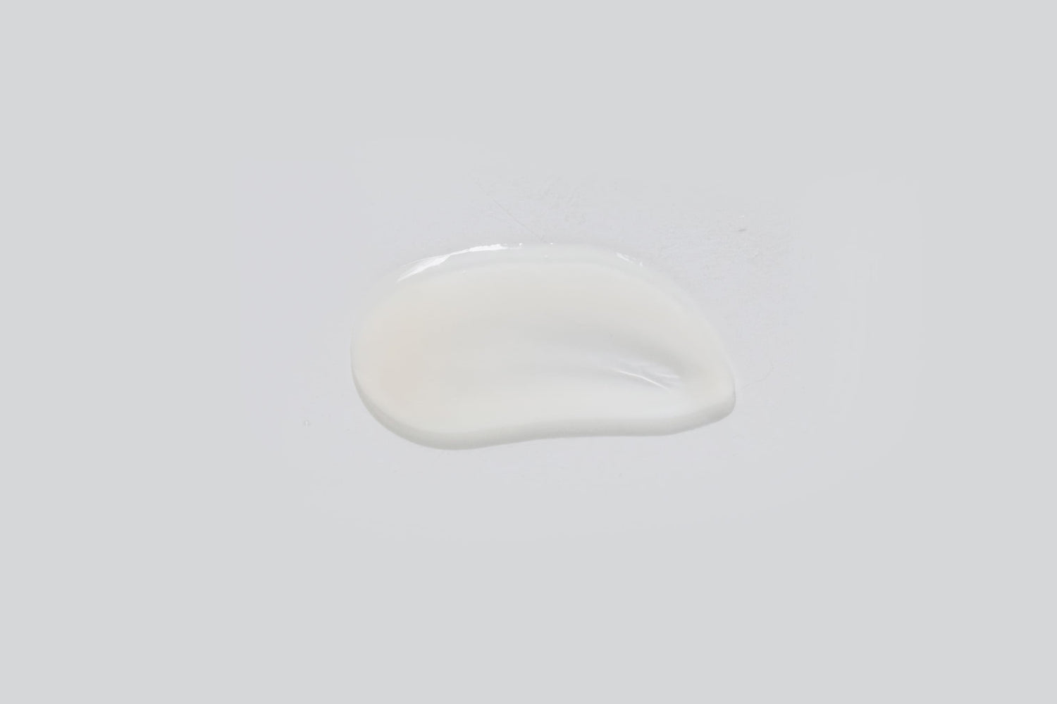 A small, irregular puddle of clear, milky-white Rejuvenating Serum 30ml rests on a plain light gray background.