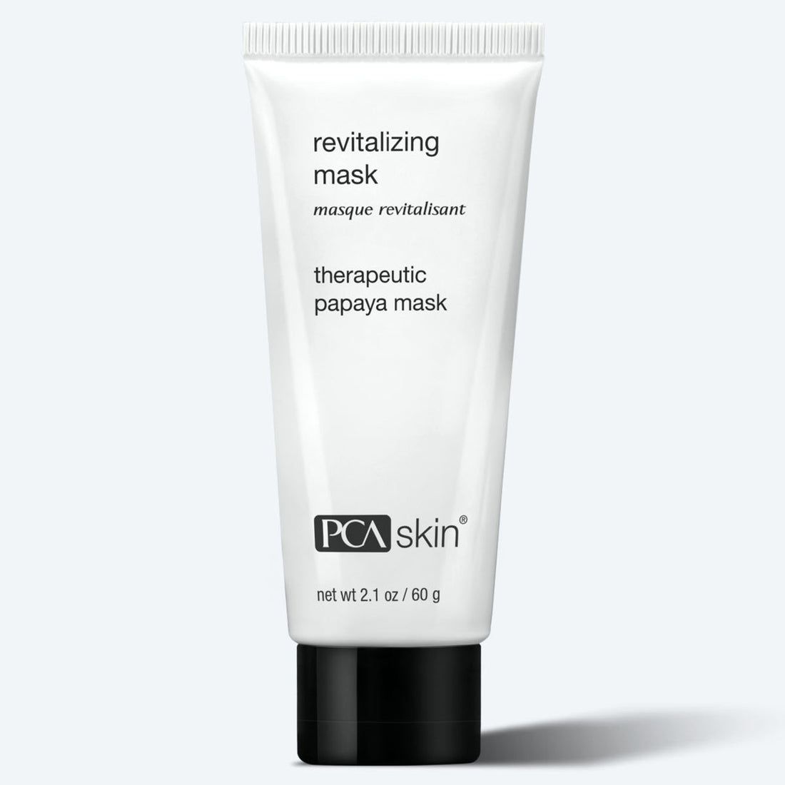 A white tube labeled "Revitalizing Mask 60g" stands upright against a light gray background; it contains 2.1 oz (60 g) of exfoliating face mask.