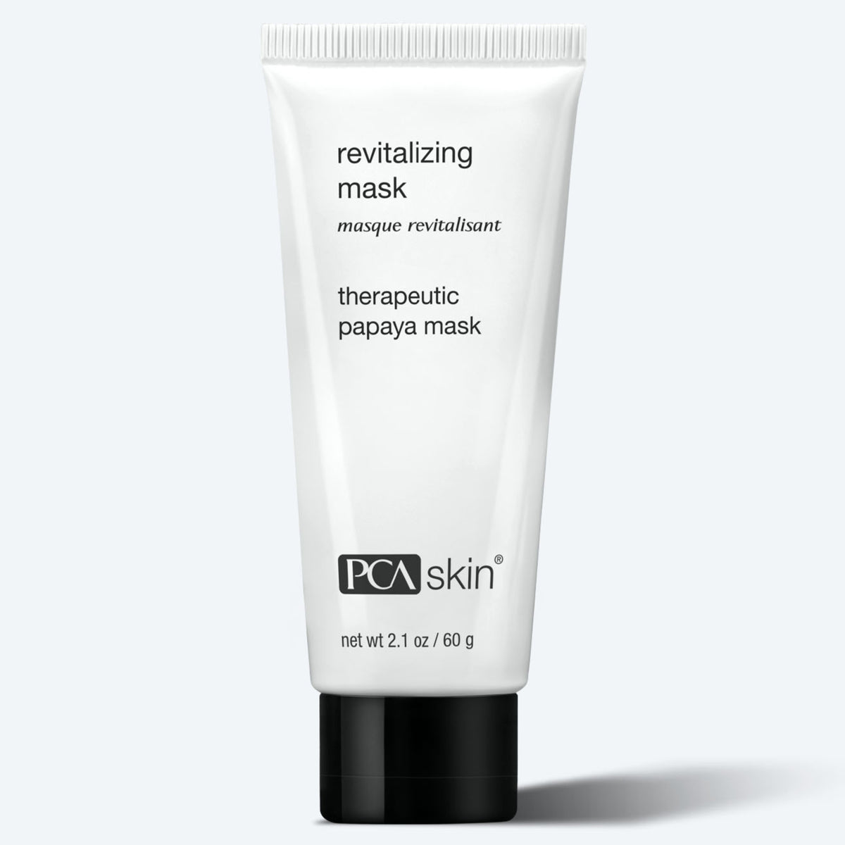 A white tube labeled "Revitalizing Mask 60g" stands upright against a light gray background; it contains 2.1 oz (60 g) of exfoliating face mask.