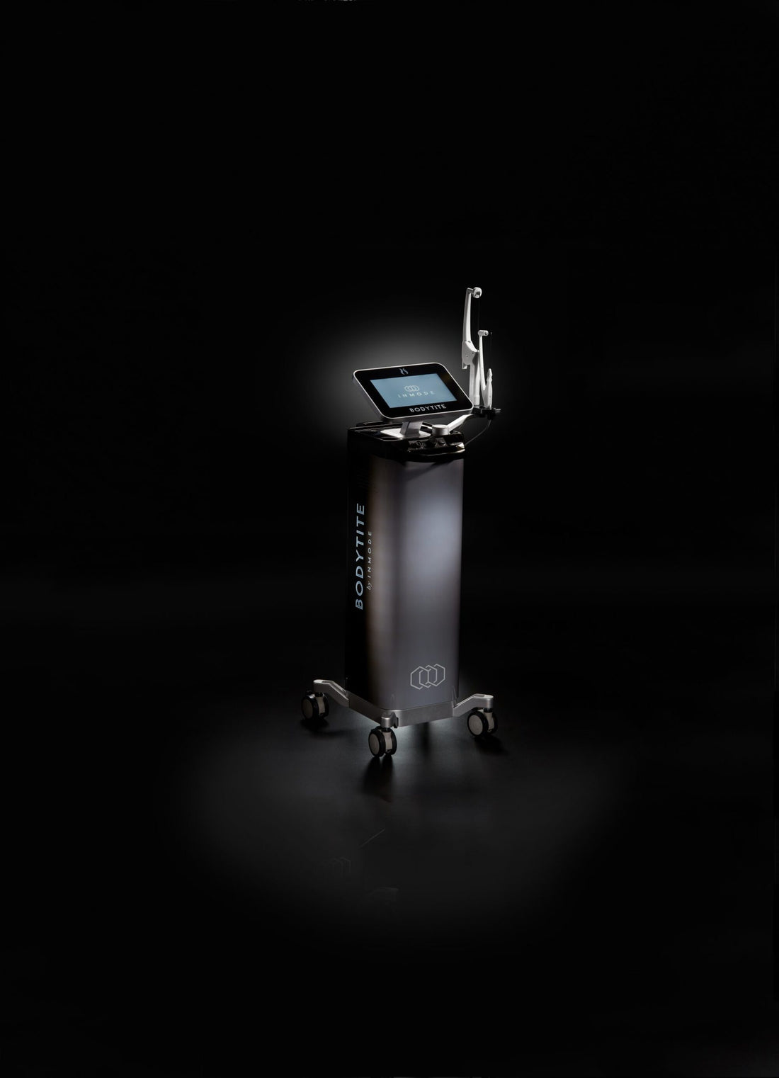 A sleek, modern medical device labeled &quot;Bodytite&quot; stands on a dark background. It features a touchscreen monitor on top and is mounted on a mobile base with four wheels for easy movement. Utilizing radiofrequency technology, this body contouring device has a minimalist design with a black and silver color scheme.