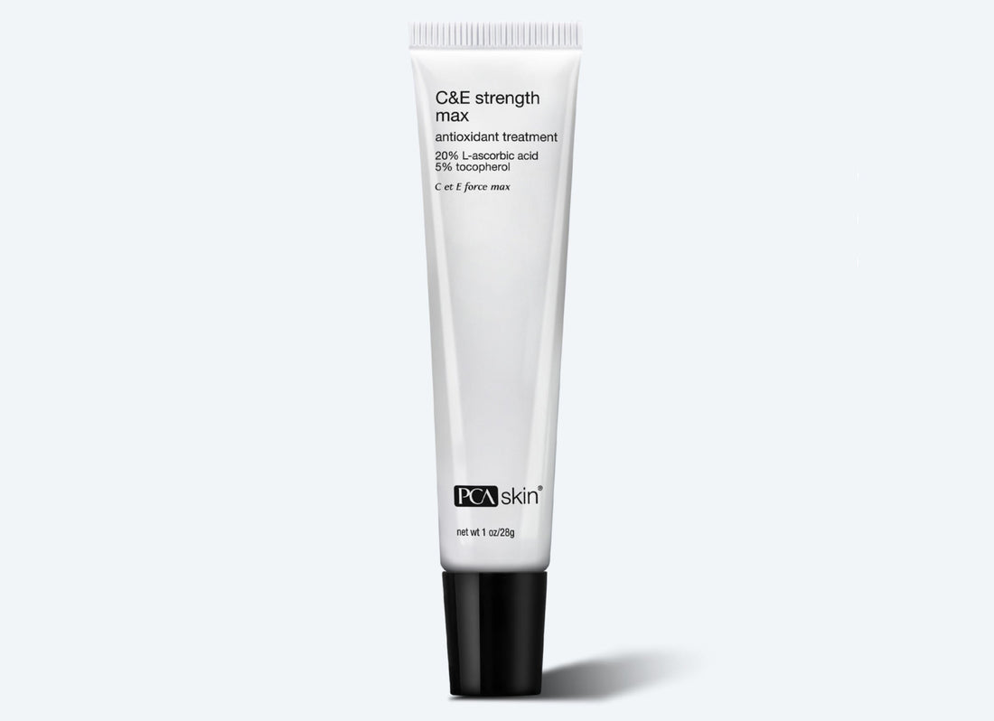 A white tube of C&amp;E Strength Max 28 g antioxidant formulation treatment. The tube features black text detailing ingredients like 20% L-ascorbic acid (Vitamin C) and 5% tocopherol, targeting fine lines and wrinkles. The product stands upright on a light gray background, with a shadow underneath.