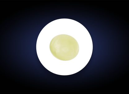 A glossy, light green sphere containing pure vitamin C sits perfectly centered on a bright white oval, set against a dark, gradient blue background. The simple, abstract composition is visually striking with contrasting colors, evoking the benefits of C&amp;E Strenght Max formulation for fine lines and wrinkles.