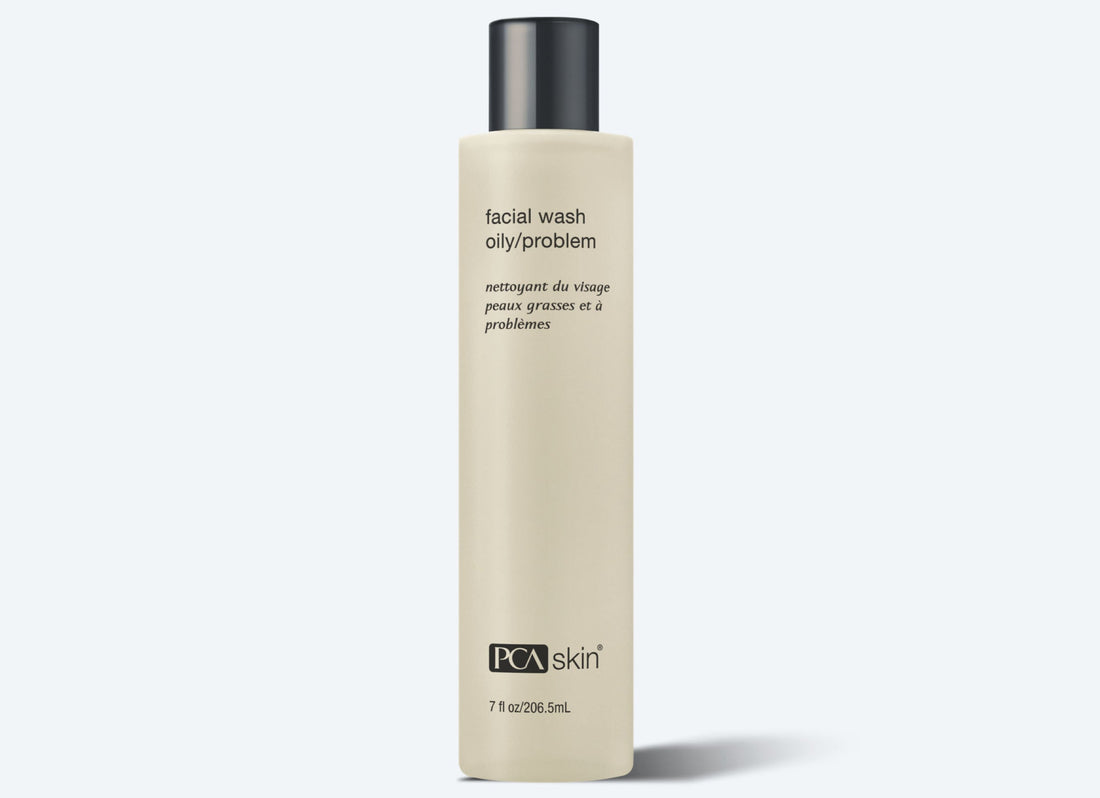 A beige bottle of Facial Wash Oily/Problem for pimple-prone skin with a black cap is displayed against a light background. Text on the bottle includes instructions in English and French. The 7 fl oz (206.5 ml) face wash effectively minimizes breakouts for oily/problem skin.