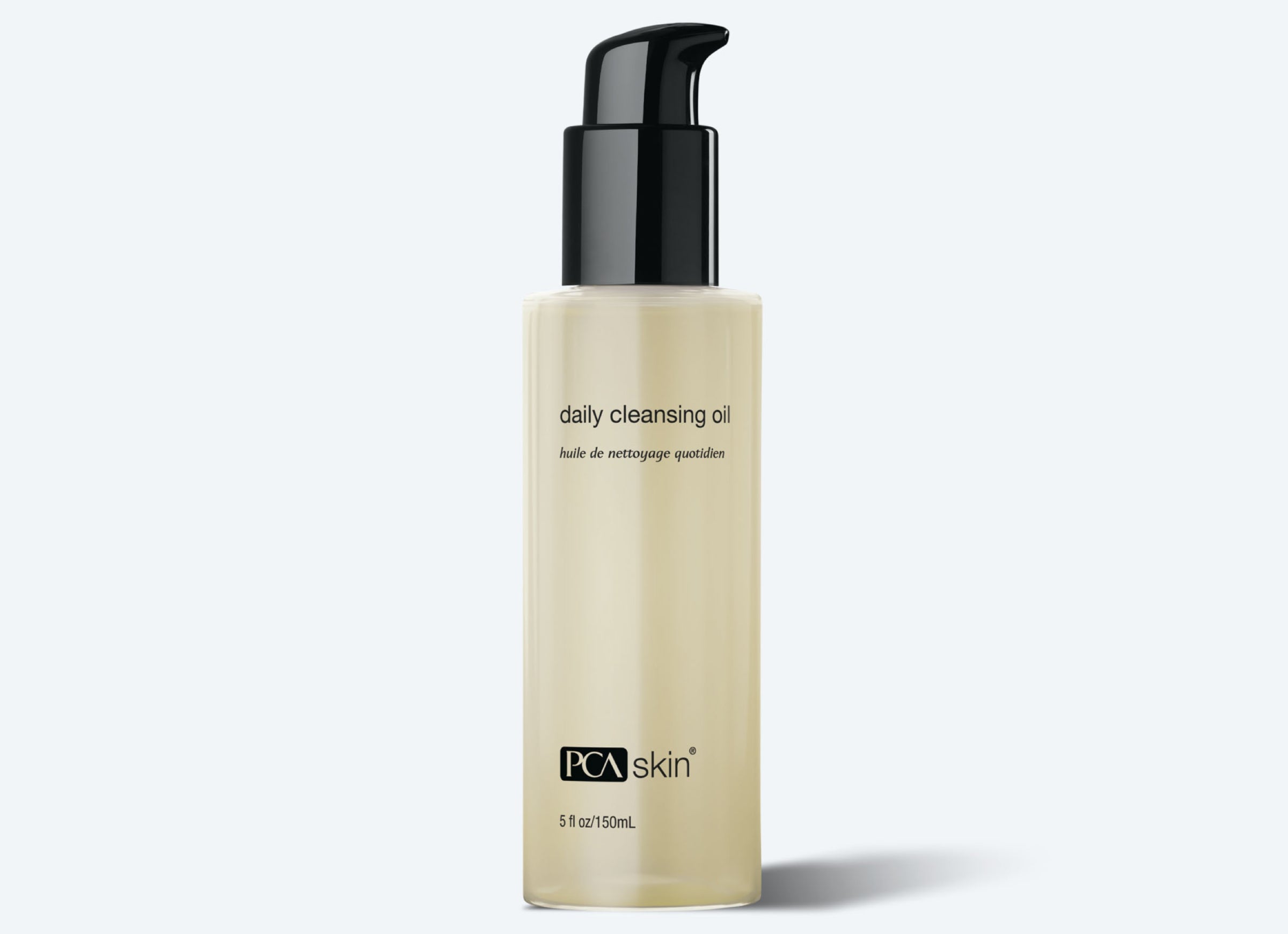 A bottle of Daily Cleansing Oil Makeup Remover. The transparent bottle with light yellow oil has a black pump dispenser and black text on the front. Effective as a makeup remover, the label includes the product name in English and French, with the brand logo at the bottom.