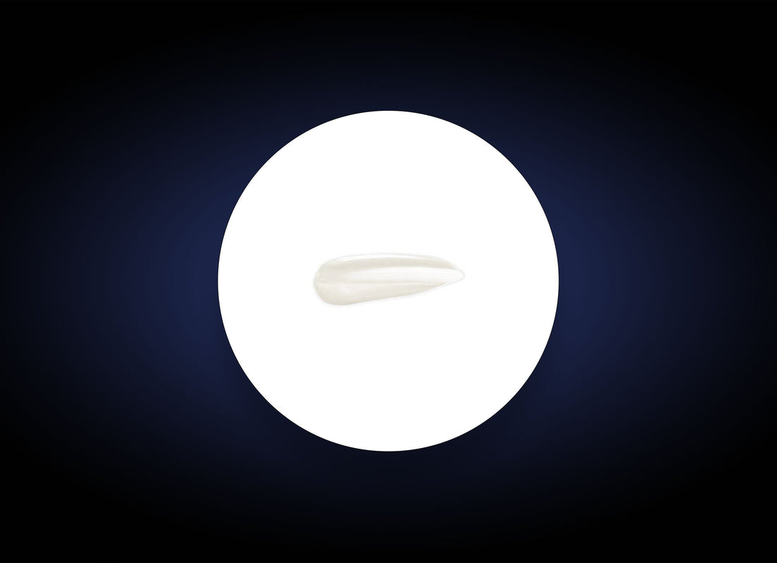 A single, smooth white tooth isolated on a circular white background, surrounded by a dark gradient border. The tooth is centered, and its elongated shape is clearly visible against the contrasting backdrop, much like an HA Lip Overnight Mask rejuvenates and plumps your lips overnight.