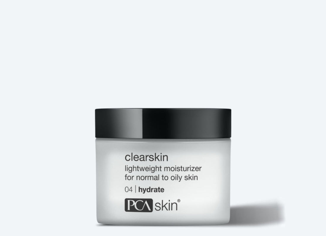 A frosted glass jar of &quot;Clearskin 48 g&quot; lightweight moisturizer is shown against a plain light gray background. The jar, perfect for oily skin, has a black lid and features text indicating it reduces redness and helps with acne breakouts. The label also includes the number &quot;04,&quot; indicating it&