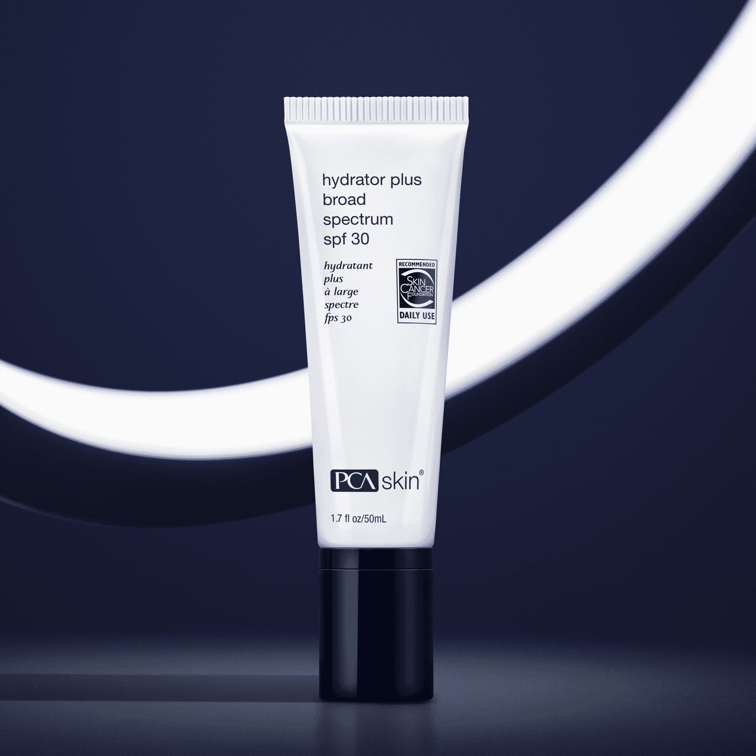 A tube of Hydrator Plus BS SPF30 stands upright against a dark, abstract background with a glowing white curve. The white tube with black text and a black cap contains 1.7 oz (50 ml) of moisturising sunscreen, perfect for dry skin needing broad-spectrum protection.