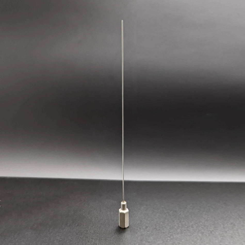 The image shows a long, slender 18 Gauge Stylette with a white base. The 18 Gauge Stylette is standing upright against a dark, gradient background. The design is minimalistic, and the 18 Gauge Stylette is prominently centered in the frame.