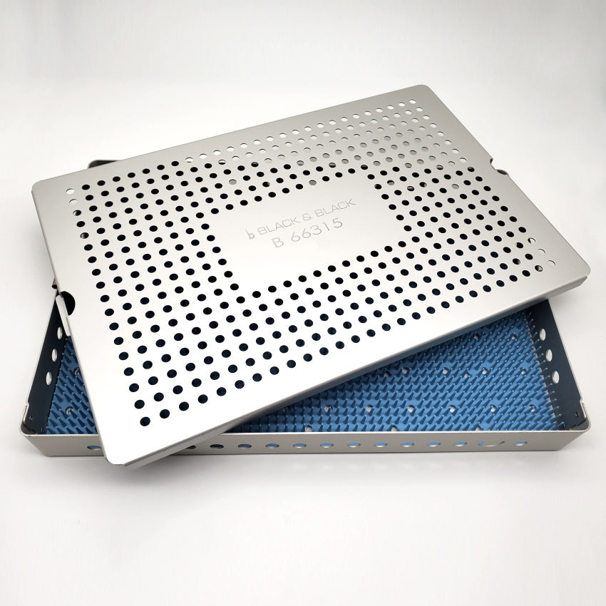 A Sterilization Tray Single Level Aluminum w/ Lid &amp; Silicone Mat, 10.5″ x 15.5″ x 1.5″ partially covers a blue spiked silicone mat. The box and lid have numerous small holes arranged in a grid pattern. The background is plain white.