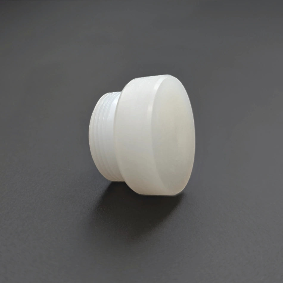 A white, cylindrical plastic cap with a ridged side, likely for screwing onto a bottle or container. It is placed on a dark, flat surface and shown at an angle, resembling the precision of Replaceable Nylon Face, for Mallet B67202 components.