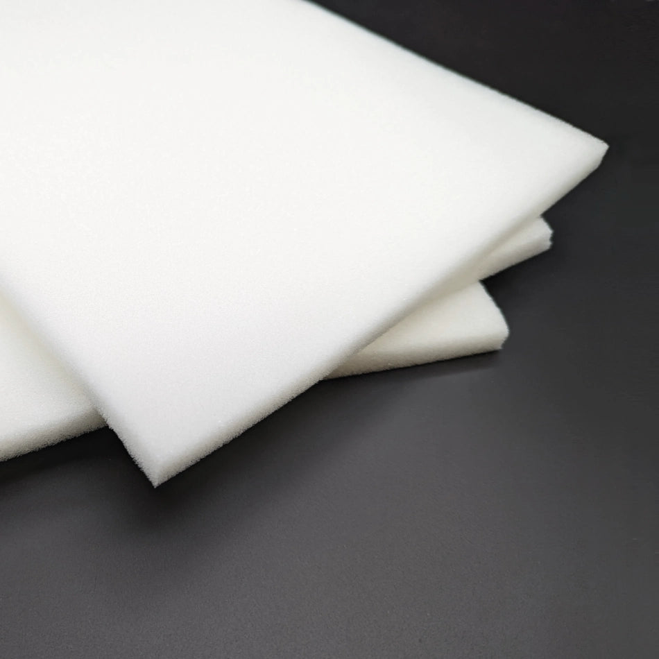 A close-up view of three white foam sheets stacked on a dark, slightly reflective surface. The foam sheets appear soft with a smooth texture, and their edges show clean, straight cuts—ideal for ContourFoam™, 1/2″ x 9″ x 14″ - Box of 50 pc to help reduce bruising and swelling.