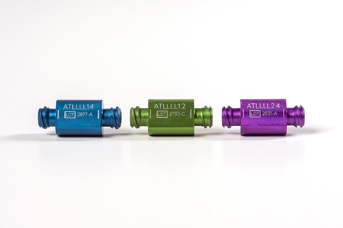 Three small, cylindrical, metallic connectors in blue, green, and purple are lined up horizontally on a white background. Each Anaerobic &amp; Sizing Transfers™ connector is labeled with a code: &quot;ATL1114,&quot; &quot;ATL1112,&quot; and &quot;ATL1124&quot; respectively, along with additional lot numbers and details.