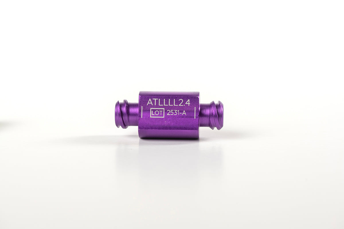 A small, cylindrical, purple metal component is centered against a white background. It has two narrow extensions on either end and is labeled &quot;ATLLLL2.4&quot; with &quot;LOT 2351-A&quot; below it. Designed for reusable transfers, it&