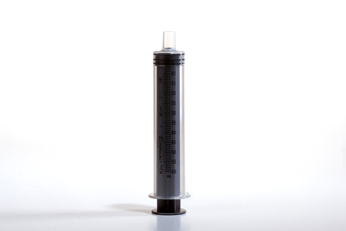 A large plastic 60cc Toomey Monoject Syringe with a clear body and black markings for measurement stands upright on a white surface. The plunger is fully extended, and there is no needle attached. The syringe, featuring a Toomey Monoject tip, is designed for non-medical purposes like cooking or crafting.