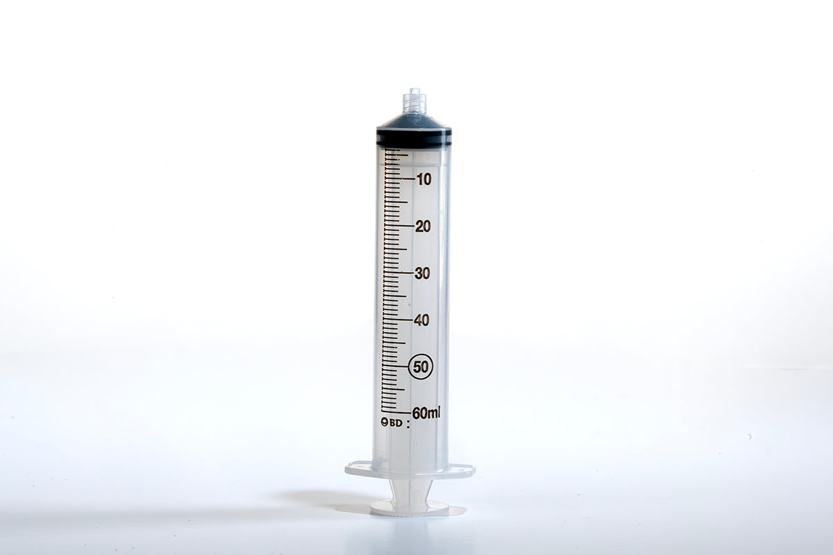 A clear, 60ml syringe standing vertically against a white background. The 60cc Luer BD Syringe features a plunger at the bottom and measurement markings labeled from 0 to 60ml along the side.