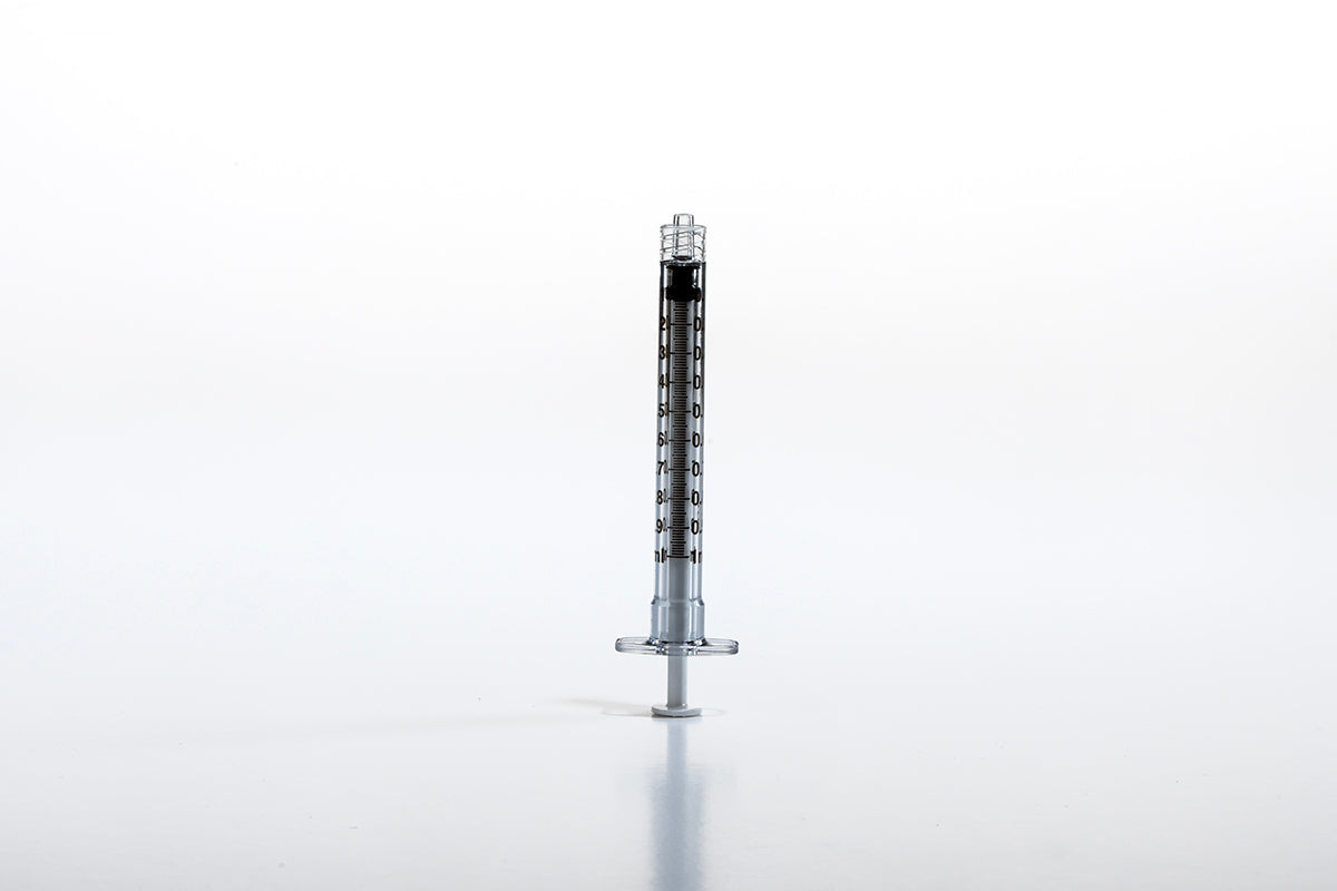 A single, transparent 1cc Luer BD Polycarbonate Syringe filled with a dark liquid stands vertically against a plain white background. Its black plunger is at the bottom, and graduation marks run along the length of the barrel. The Luer Lock tip ensures secure attachment for precise application.