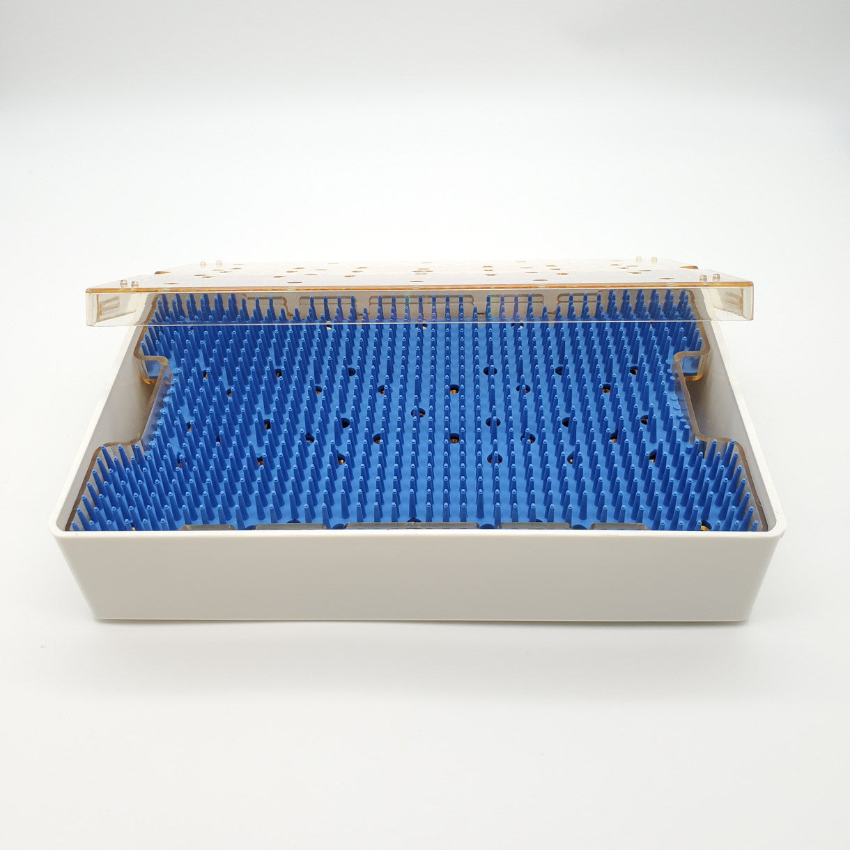 A rectangular white container with a beige lid, partially open, revealing a blue spiky interior designed to store and sterilize items. The spikes cover the entire surface inside the clean, empty Sterilization Tray Double Level; Base, Lid, Insert Tray, Mat, 10″ x 6″ x 2″. The background is plain white.