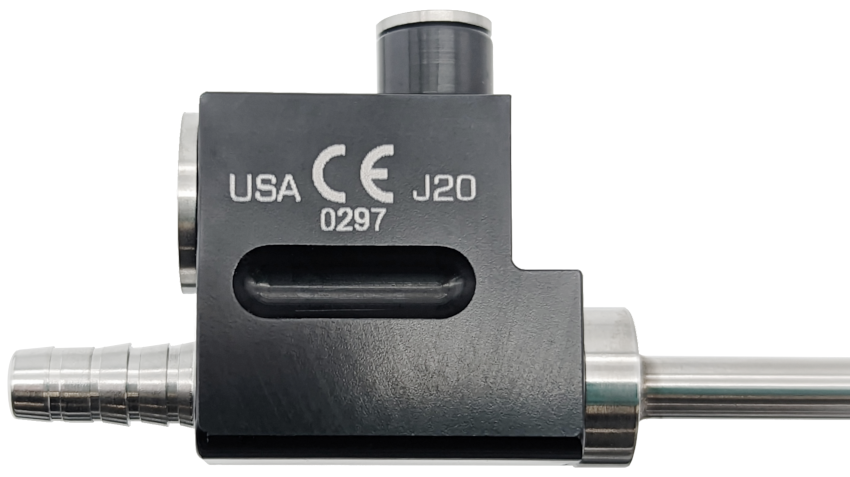 A close-up image of a metallic mechanical part featuring various components, including a cylindrical piece, a tubular element, and an L-shaped body with engraved text &quot;USA&quot; and &quot;J20&quot; along with a CE mark and the number &quot;0297&quot;. This Accelerator Cannula, MicroAire®-Type Power Hub is also autoclavable for sterilization.