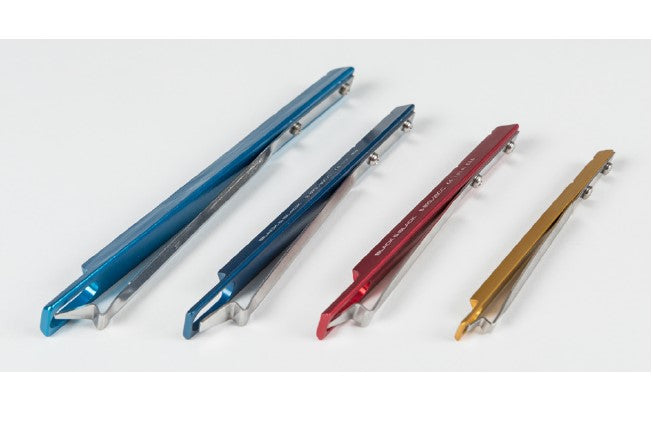 A row of four differently sized and colored Syringe Snap Locks displayed horizontally. From left to right, the colors are blue, dark blue, red, and gold. Each Syringe Snap Lock has sleek, angular design details and is set against a white background.